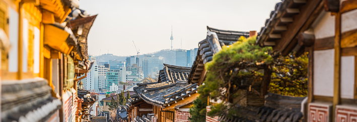 The iconic spire of Namsan Tower overlooking tourists visiting the traditional wooden homes of Bukchon Hanok village in Seoul, South Korea’s vibrant capital city.