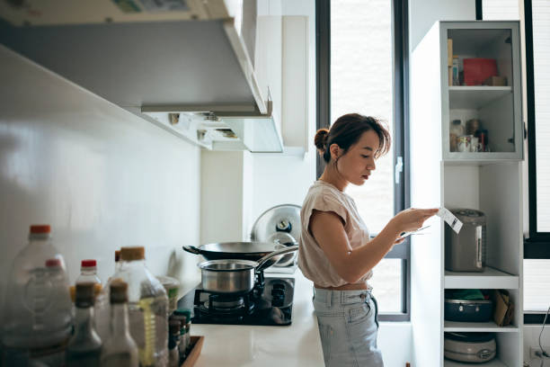 donne asiatiche che esaminano la ricevuta della spesa a casa - spending money foto e immagini stock