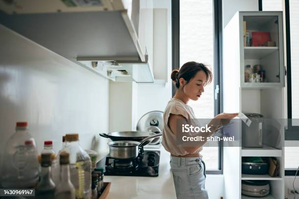 Asian Women Examining The Shopping Receipt At Home Stock Photo - Download Image Now - Inflation - Economics, Cost of Living, Home Finances