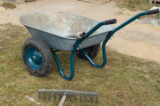 Wheelbarrow in the garden. agricultural working. rake lies on the ground. gardening process