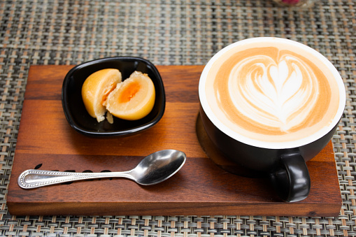 Hot coffee latte art serve with chinese pastry moon cake serve on wooden tray for travelers thai people rest relax eat and drinks at cafe restaurant shop in Bangkok, Thailand