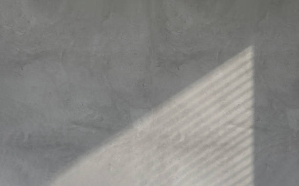 istock Beautiful soft sunlight and shadow from window blinds on empty concrete wall background 1430971299
