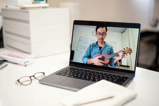 Close-up shot of a computer screen with mature adult man giving online ukulele music lessons in Japan