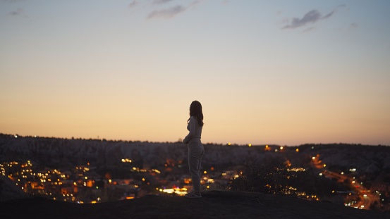 A young female tourist is standing at the edge of cliff in Cappadocia Türkiye.