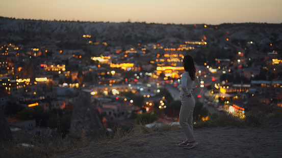 A young female tourist is standing at the edge of cliff in Cappadocia Türkiye.