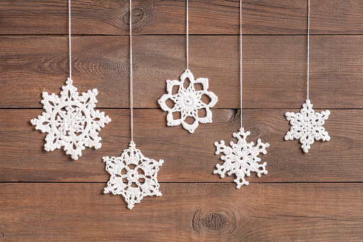 Handmade white crochet snowflakes stars on wooden background. This file is cleaned and retouched.