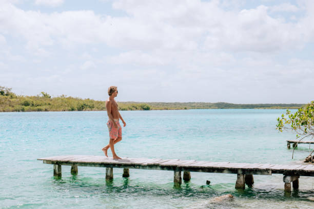 istock Young man walking on pier above blue lagoon contemplates the view 1430974689
