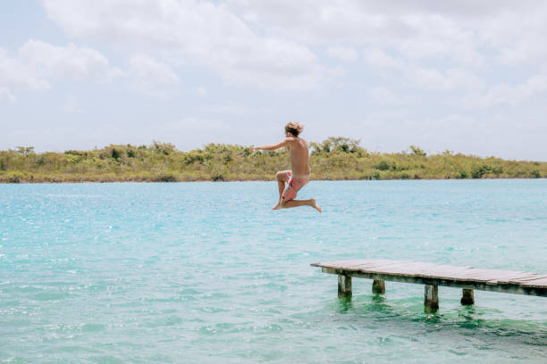istock Happy young man jumping from pier into beautiful lake 1430974704