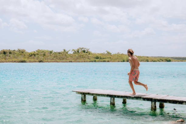 istock Happy young man jumping from pier into beautiful lake 1430974863