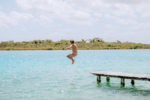 istock Happy young man jumping from pier into beautiful lake 1430974987