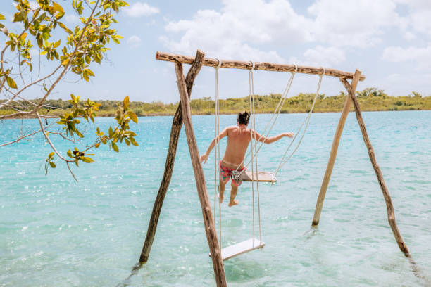 istock Young man jumps from swing onto beautiful lagoon 1430975230