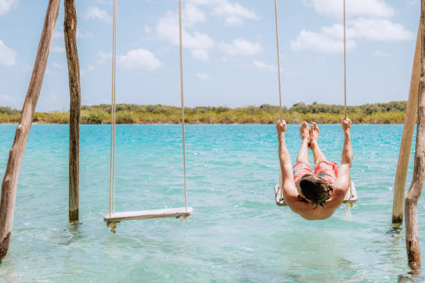 istock Young man having fun on swing in a beautiful lagoon on a sunny day 1430975308