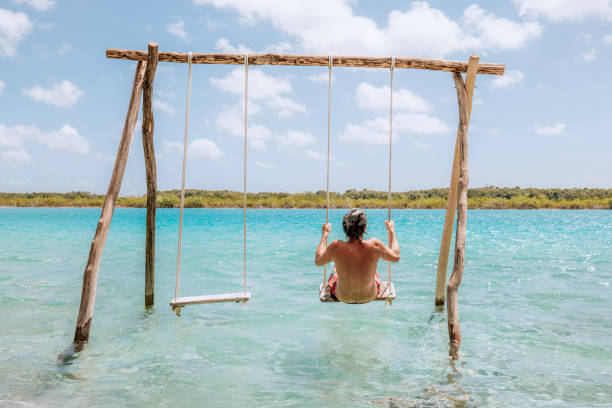 istock Young man having fun on swing in a beautiful lagoon on a sunny day 1430975433
