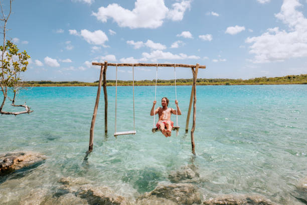 istock Young man having fun on swing in a beautiful lagoon on a sunny day 1430975479