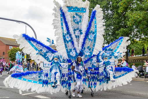 Leeds, United Kingdom - August 29, 2022: Woman in giant blue and white costume in Leeds West Indian Carnival Parade on Aug 29, 2022 in Leeds, United Kingdom