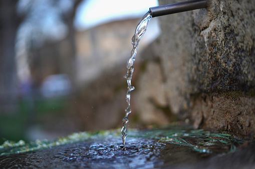 fountain pouring water through a tube that comes out of the stone