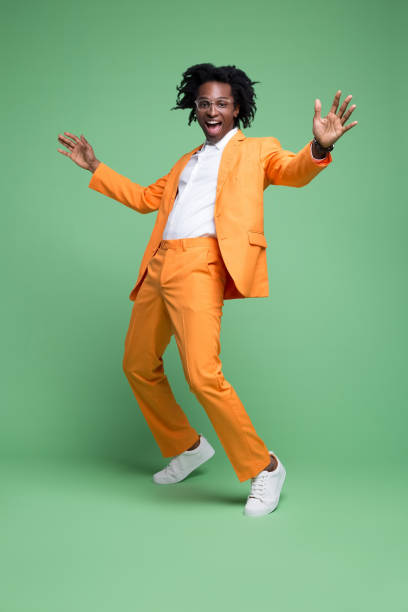 Portrait of excited elegant man Full length portrait of elegant man wearing orange suit and white shirt laughing at camera. Studio shot, green background. people dancing stock pictures, royalty-free photos & images