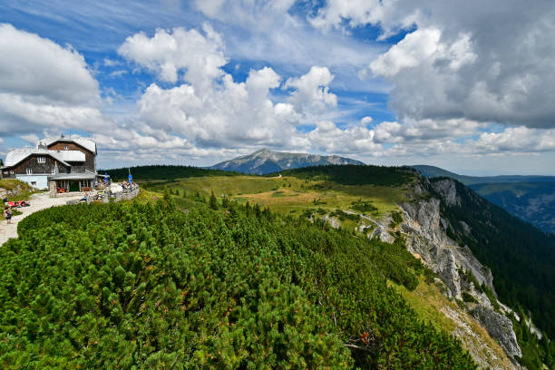 Hirschwang, Austria - August 10, 2022: Unknown hikers take a break at the mountain inn called Ottohaus on Rax mountain in Lower Austria, Schneeberg mountain in background, both are part of the Vienna Alps