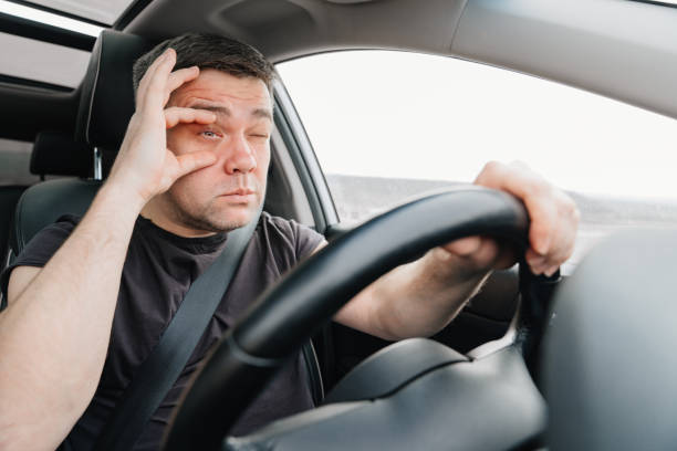 istock a sleepy man with closing eyes drives a car on the highway 1430982542