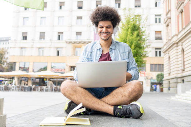 istock Man smiling when using laptop and headphones for his studies 1430984722