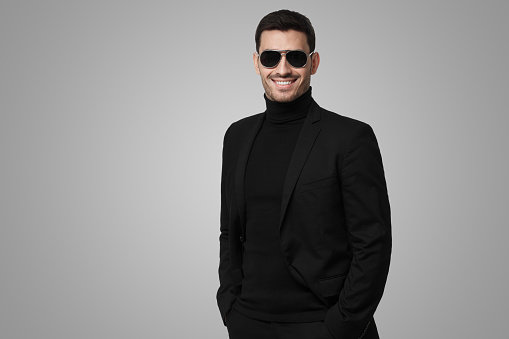 Serious body guard or secret agent wearing suit and sunglasses, isolated on gray background