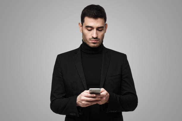 istock Male in black clothes holding phone, typing or browsing with concentrated face 1430989551