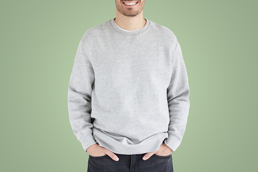 Young man in gray sweatshirt, standing isolated on green background. No face photo