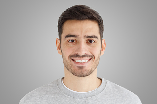 Close-up daylight portrait of young smiling handsome man isolated on gray background