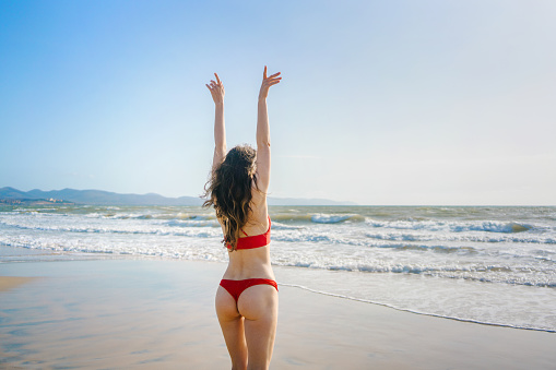 Cheerful young woman enjoying sunny weather at the beach