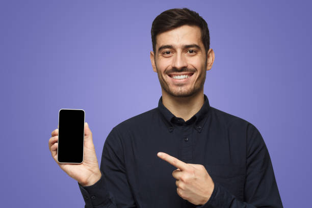istock Young handsome smiling man holding and showing with finger blank smart phone with copyspace for ads 1430993152