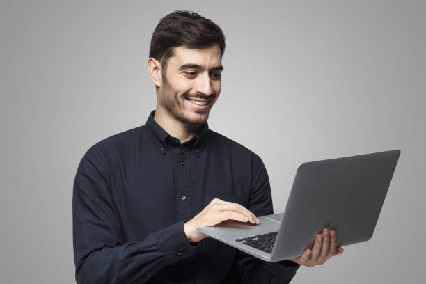istock Young modern businessman standing with laptop and happy smile, using touchpad 1430993357