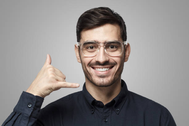 istock Young man showing gesture as if asking to calll him, looking confident, isolated on gray 1430993962