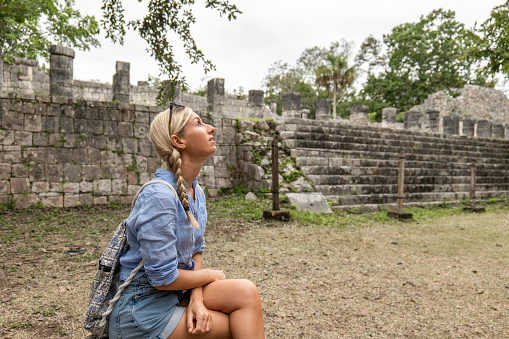 Cheerful female tourist discovering Mayan pyramids in Yucatan, Mexico.\nShe walks around the temple.