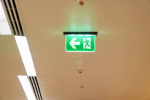 istock Arrow light box sign of EMERGENCY FIRE EXIT is hung on the ceiling in hospital,Ideas for fire incidents or evacuation drills. 1431001266