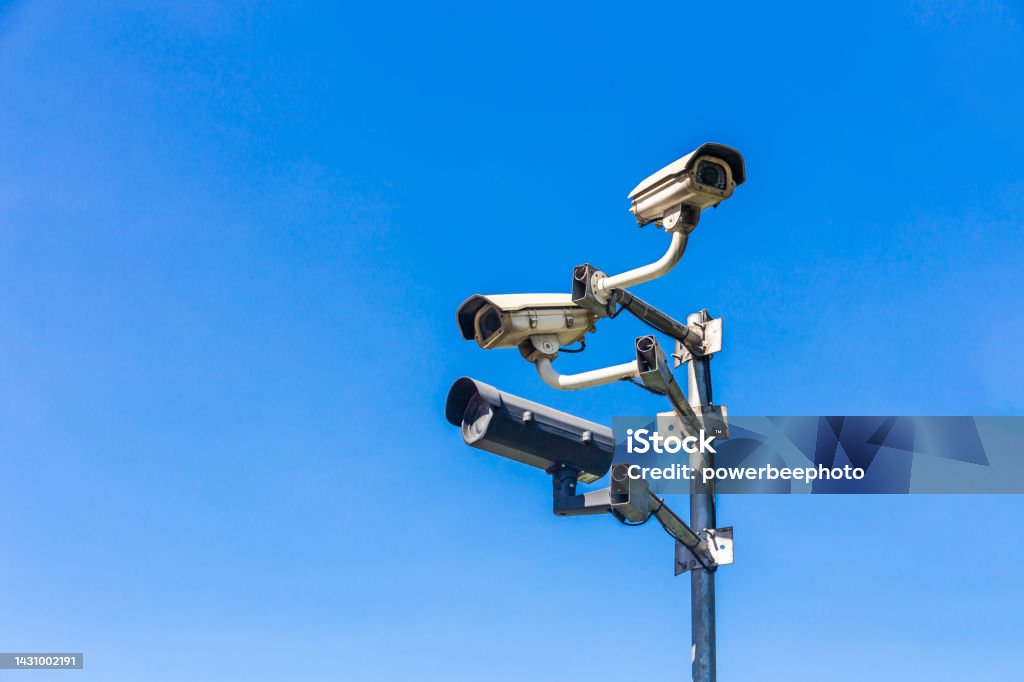 Old security camera or CCTV sits on a pole with a sky background. Pole Stock Photo