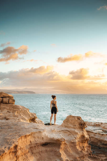 istock Woman standing on a cliff overlooking spectacular sunset 1431002910