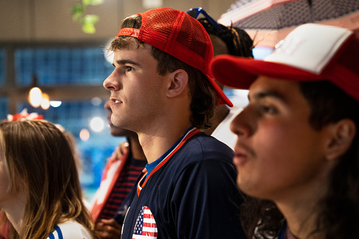 Mid-shot of group of young friends watching USA national team game at crowded sports bar