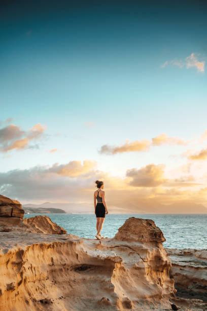 istock Woman standing on a cliff overlooking spectacular sunset 1431005670