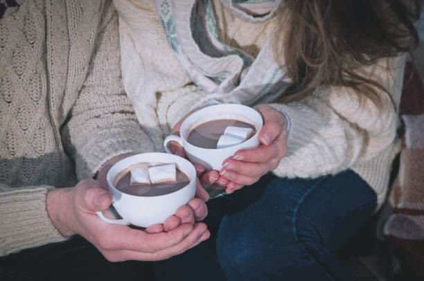 istock man and woman sitting and holding cocoa with mashmellow 1431007922