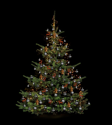 Released decorated Christmas tree against dark background