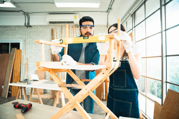 istock Carpenters using a surface level measuring tool for the consistency of chair armrests. 1431015959
