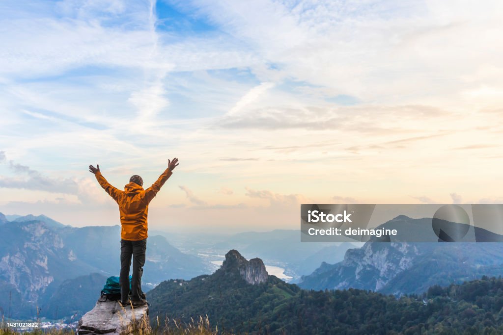 Happy hiker with raised arms on top of the mountain Mountain Stock Photo
