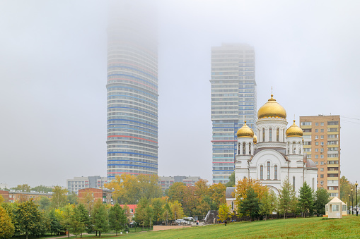Church of Saints Equal-to-the-Apostles Cyril and Methodius. Modern houses and houses of the Soviet period. Heavy fog in Moscow, Russia. October 2022
