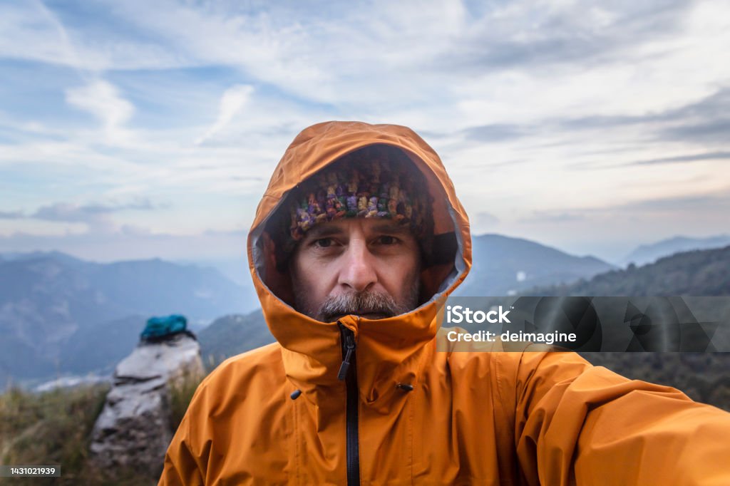 Mature man  with rain jacket in the mountains looking at camera Men Stock Photo