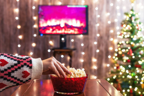 Christmas eve. Alone woman watching tv and eating popcorn. Home cinema. Cropped, close up stock photo