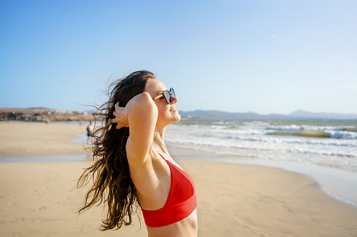 Happy young woman enjoying sunny weather at the beach
