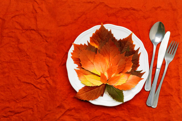 istock Autumn table setting, plate, knife, fork on red linen tablecloth. Top view white plate decorated fall red colored leaves and cutlery.  Autumn home and table decor. Seasonal holiday natural decor 1431027744