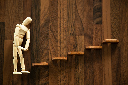 Wooden men stands in front of stairs