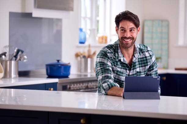 istock Man Using Digital Tablet In Kitchen To Work From Home Book Holiday Or Shop 1431030351