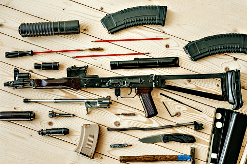Disassembled rifle with cleaning tools on table of weapons workshop close up